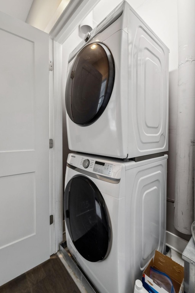 laundry room featuring laundry area, dark wood-style floors, and stacked washer and clothes dryer