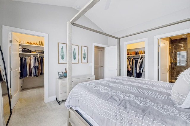 bedroom featuring light carpet, vaulted ceiling, a closet, and a walk in closet