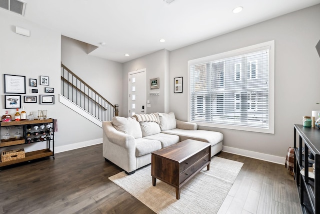 living room featuring dark wood-style floors, visible vents, stairway, and baseboards