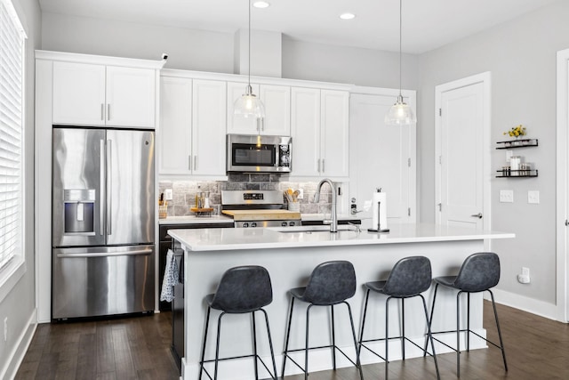 kitchen with a center island with sink, stainless steel appliances, light countertops, white cabinets, and a sink