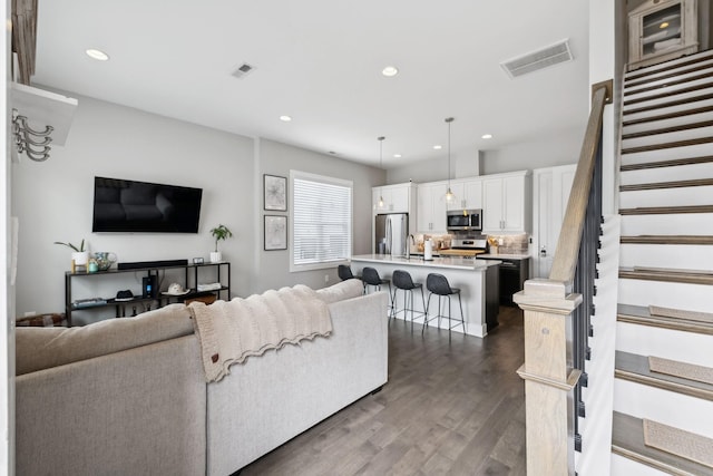 living room featuring dark wood-style floors, stairway, visible vents, and recessed lighting