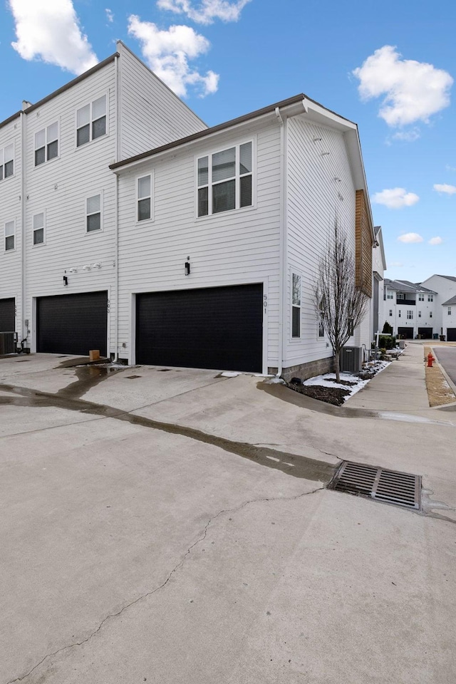 view of home's exterior featuring driveway, an attached garage, and central air condition unit