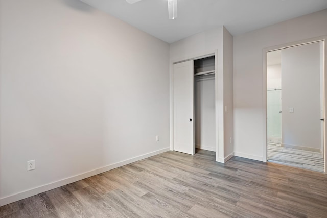 unfurnished bedroom with light wood-style floors, ceiling fan, baseboards, and a closet