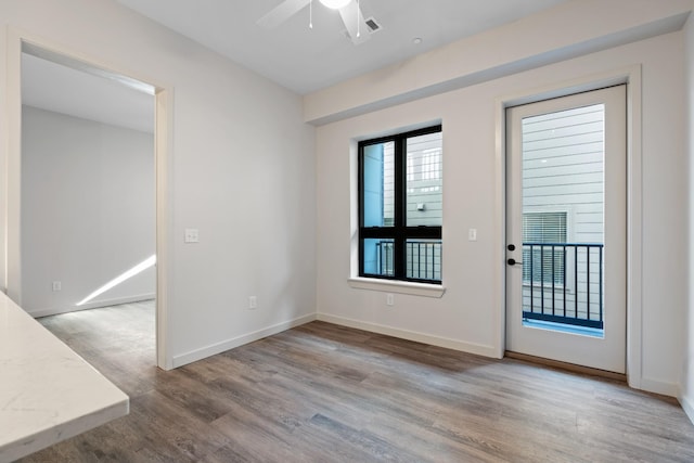 spare room with light wood-type flooring, ceiling fan, and baseboards