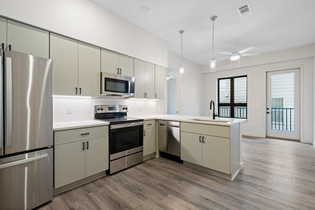 kitchen with visible vents, appliances with stainless steel finishes, a peninsula, light countertops, and a sink