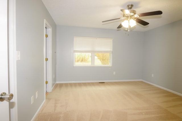 unfurnished room featuring light carpet, a ceiling fan, and baseboards