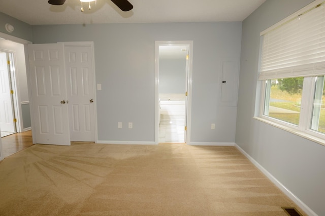 unfurnished bedroom featuring baseboards, ensuite bathroom, visible vents, and light colored carpet