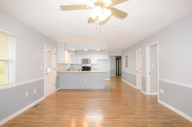 unfurnished living room featuring a textured ceiling, light wood-style flooring, and baseboards