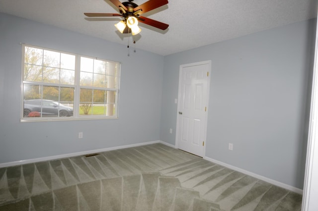 carpeted spare room with a wealth of natural light, a textured ceiling, and baseboards