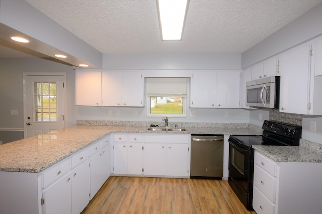 kitchen with stainless steel appliances, white cabinets, a sink, and a peninsula