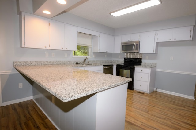 kitchen featuring white cabinets, stainless steel microwave, electric range, and a peninsula