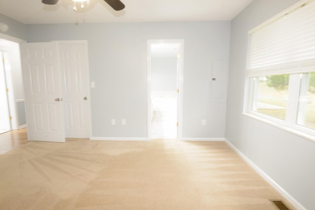 unfurnished bedroom with light carpet, a ceiling fan, visible vents, baseboards, and ensuite bath