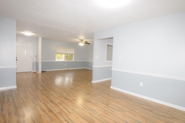 spare room featuring light wood-type flooring, ceiling fan, a textured ceiling, and baseboards