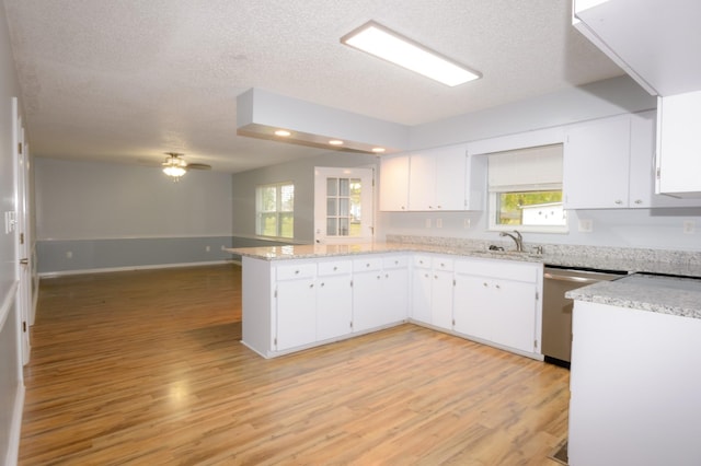 kitchen with open floor plan, stainless steel dishwasher, a sink, and white cabinetry