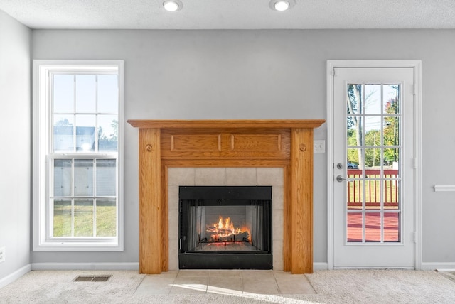 room details with baseboards, visible vents, a tiled fireplace, carpet, and a textured ceiling