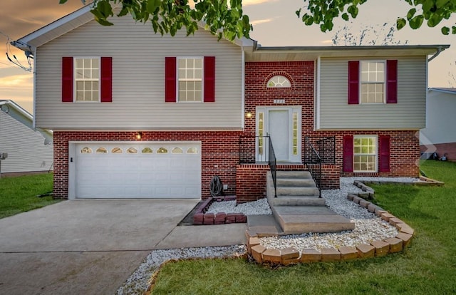 raised ranch featuring driveway, a garage, and brick siding