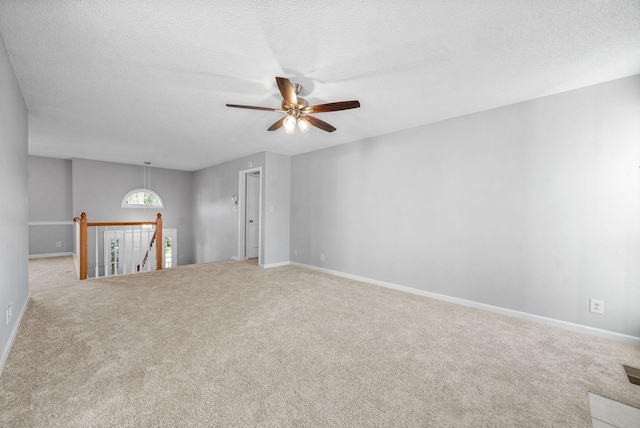 spare room with a textured ceiling, ceiling fan, carpet, and baseboards