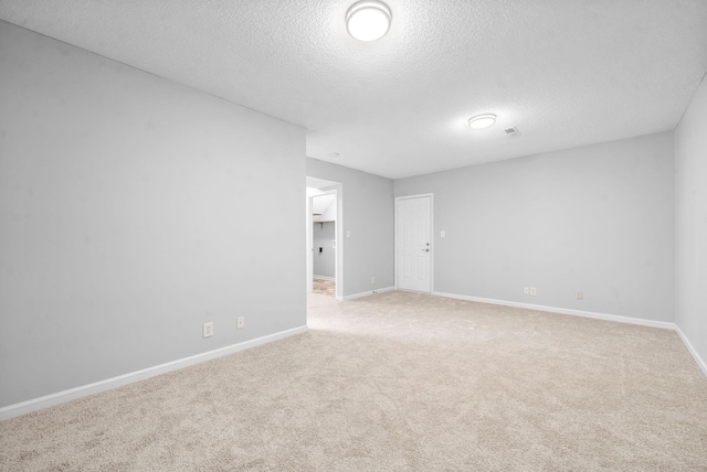 empty room with baseboards, a textured ceiling, and light colored carpet