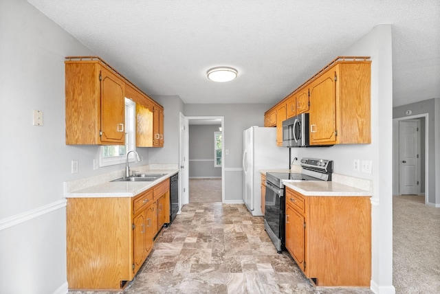 kitchen featuring brown cabinets, stainless steel appliances, light countertops, a sink, and baseboards