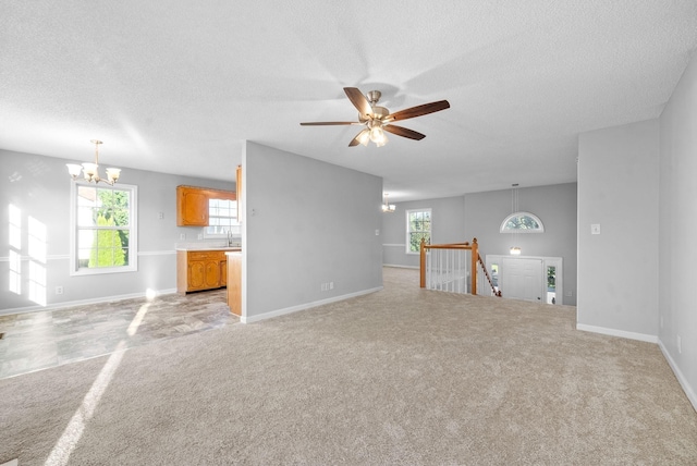 unfurnished living room with light carpet, a textured ceiling, baseboards, and a sink