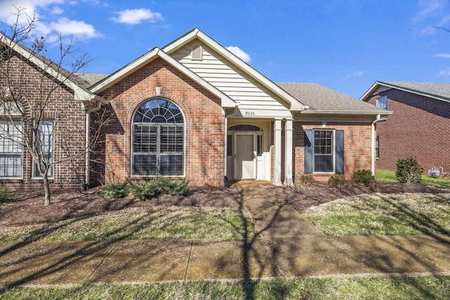 single story home featuring roof with shingles and brick siding