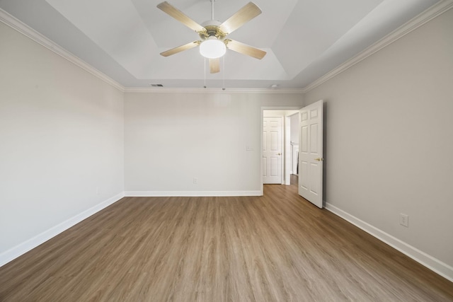 spare room featuring wood finished floors, a raised ceiling, a ceiling fan, and baseboards