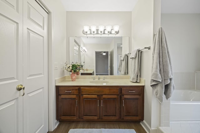 bathroom featuring a garden tub, wood finished floors, and vanity