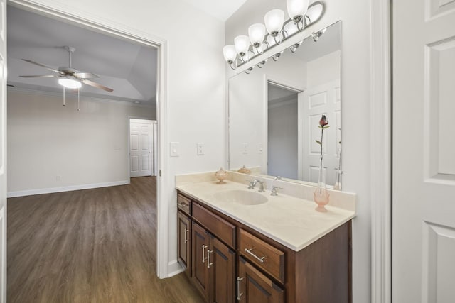 bathroom featuring baseboards, ceiling fan, ornamental molding, wood finished floors, and vanity