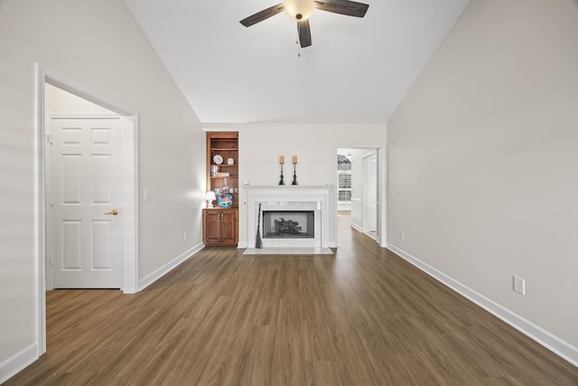 unfurnished living room with a fireplace with flush hearth, a ceiling fan, baseboards, vaulted ceiling, and dark wood-style floors