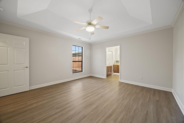 unfurnished room featuring wood finished floors, a raised ceiling, and baseboards