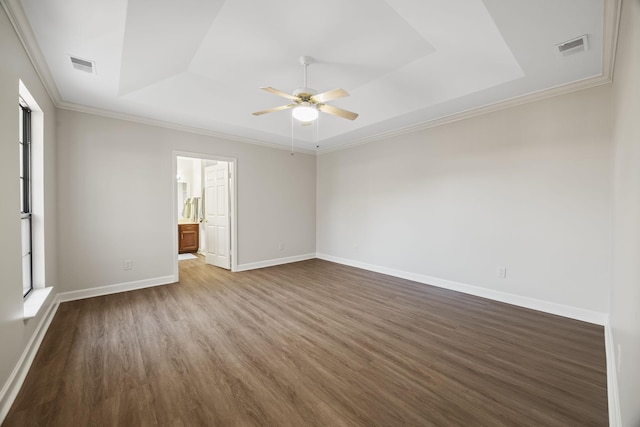 interior space with baseboards, visible vents, dark wood-type flooring, a tray ceiling, and crown molding