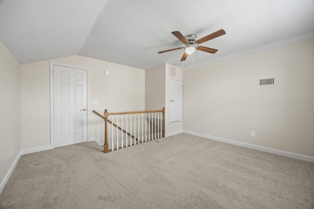 carpeted empty room with lofted ceiling, visible vents, ceiling fan, and baseboards