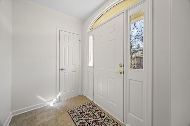 foyer entrance featuring crown molding and baseboards