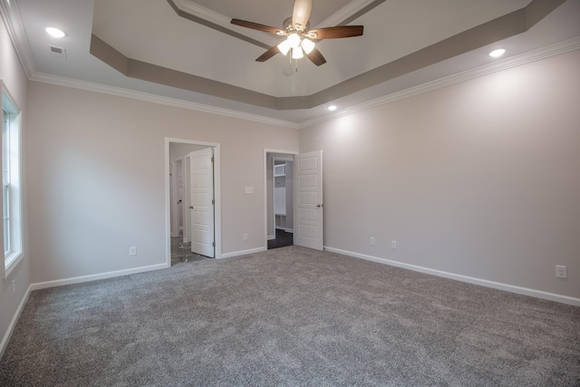 interior space featuring crown molding, a raised ceiling, carpet flooring, ceiling fan, and baseboards