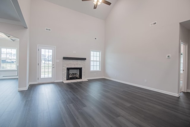 unfurnished living room featuring dark wood-style floors, baseboards, visible vents, and a stone fireplace