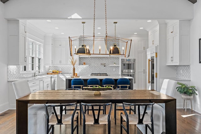 kitchen featuring hanging light fixtures, a kitchen bar, a kitchen island, and white cabinets