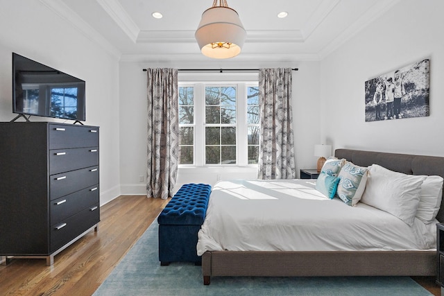 bedroom featuring baseboards, a raised ceiling, wood finished floors, crown molding, and recessed lighting