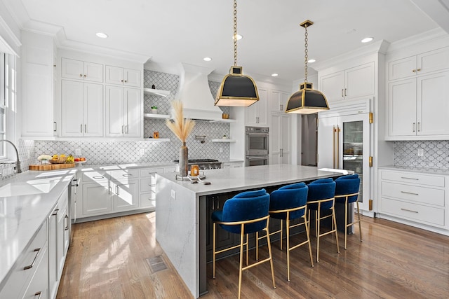 kitchen with stainless steel appliances, a sink, white cabinetry, a center island, and open shelves