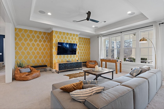 living room with wallpapered walls, an accent wall, ornamental molding, and a raised ceiling