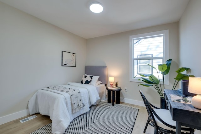 bedroom featuring light wood-type flooring, visible vents, and baseboards