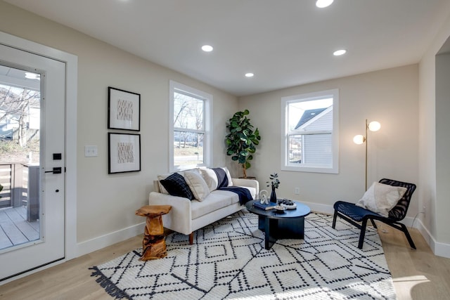 living area featuring baseboards, light wood-type flooring, and recessed lighting