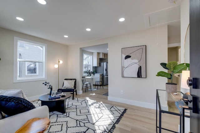 living area featuring baseboards, light wood-style flooring, attic access, and recessed lighting