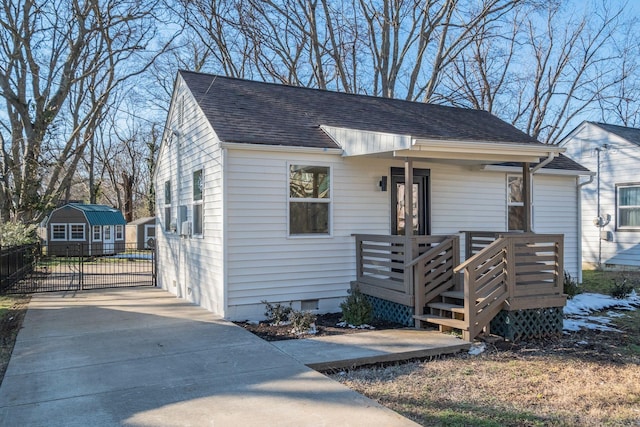 bungalow-style home with concrete driveway, a shingled roof, crawl space, and an outdoor structure