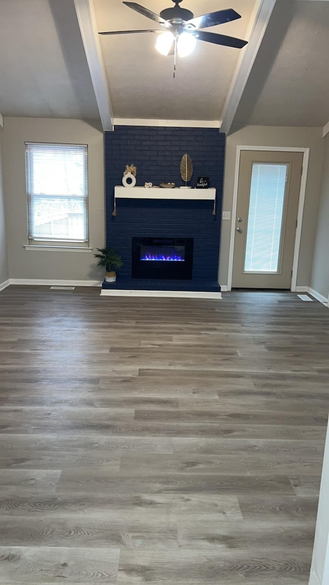 unfurnished living room with lofted ceiling, wood finished floors, a glass covered fireplace, and baseboards