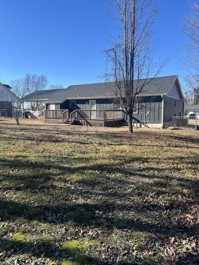 back of property with a carport, a deck, and a lawn