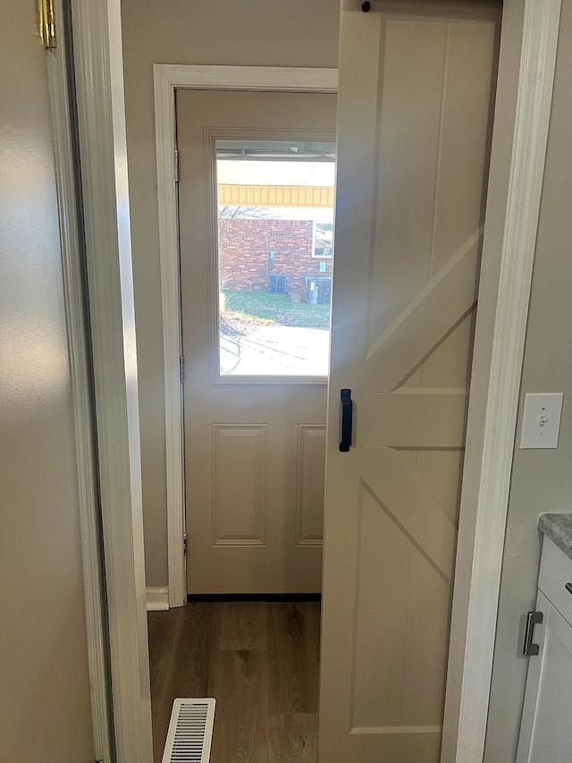 doorway to outside featuring visible vents and dark wood-style flooring