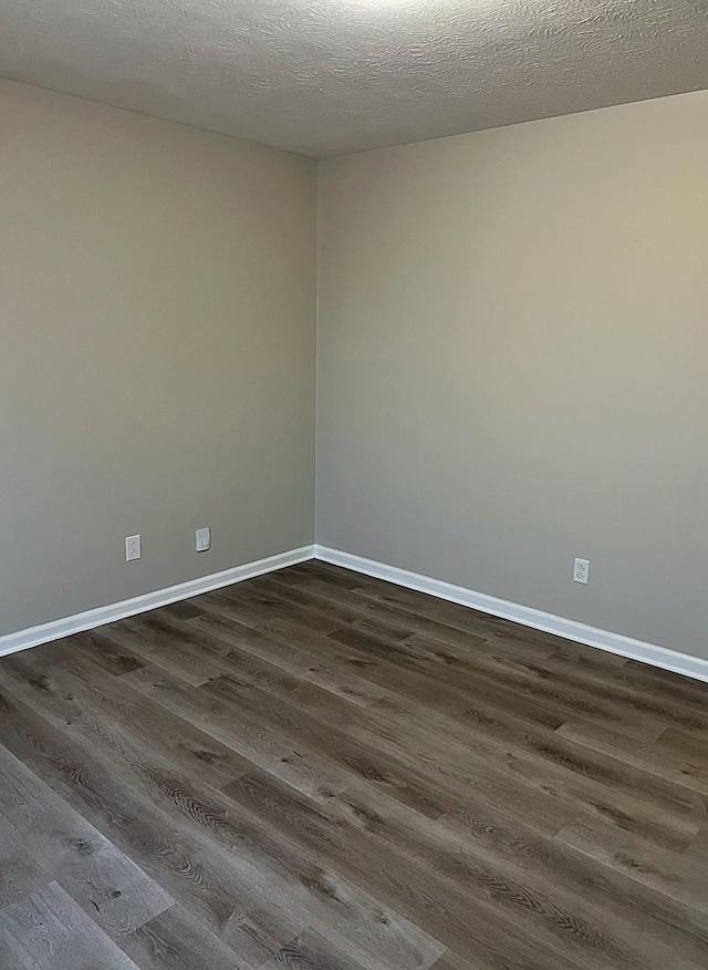 unfurnished room with dark wood-type flooring, a textured ceiling, and baseboards