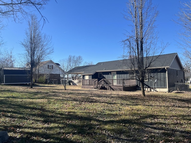 back of house featuring a storage unit, a deck, and a lawn