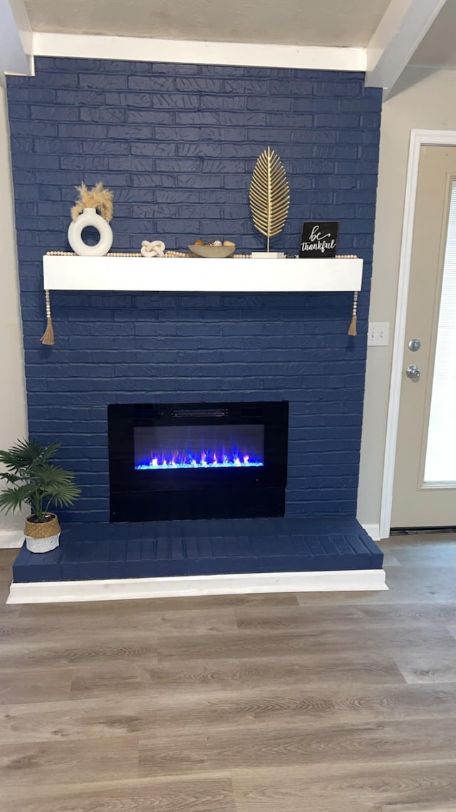 details featuring a brick fireplace and wood finished floors