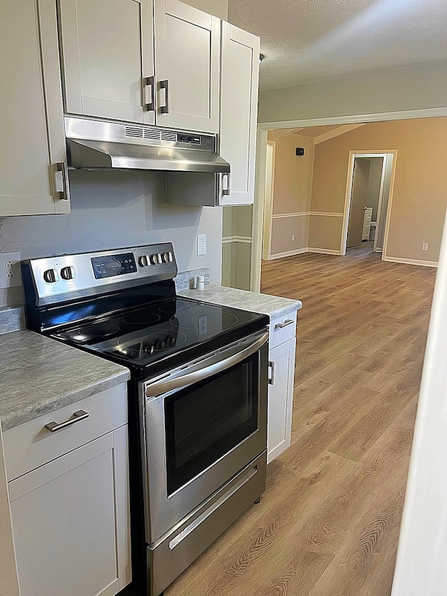 kitchen with under cabinet range hood, white cabinetry, stainless steel electric stove, and light countertops